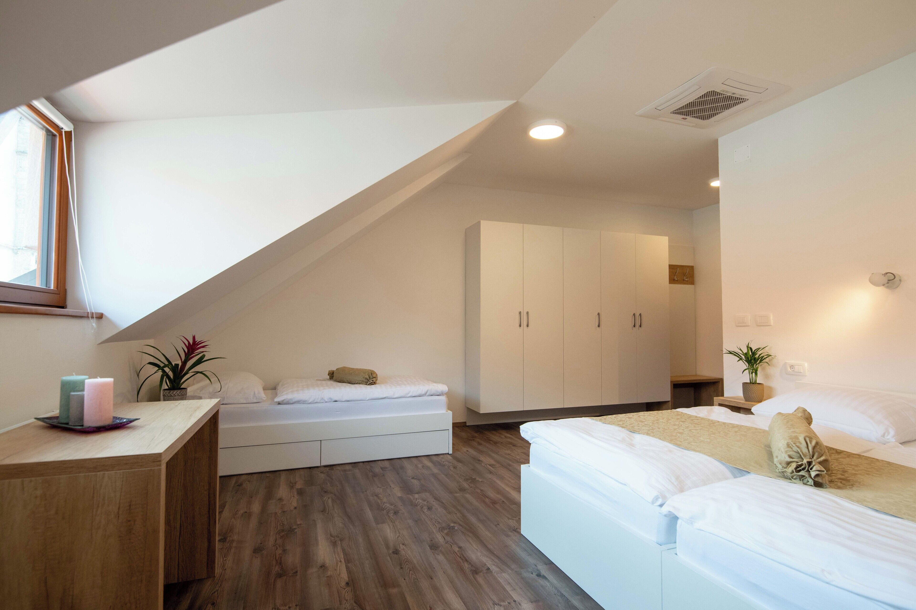 A modern bedroom with a loft bed, a bedside table with candles, and a large wardrobe.