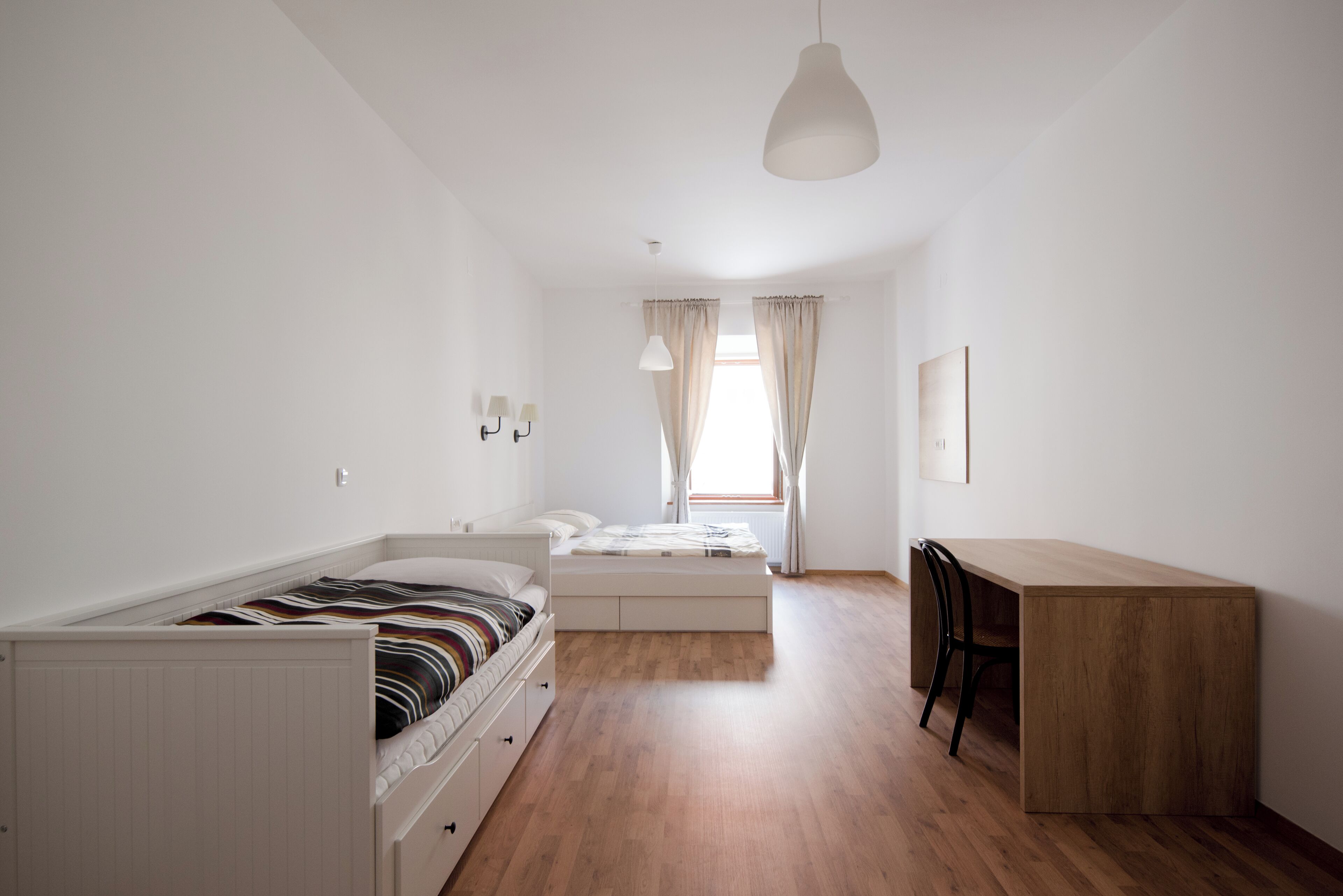 A bedroom with a bed, a desk, and a chair.