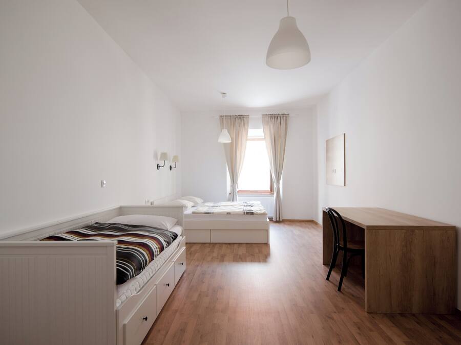 A bedroom with a bed, a desk, and a chair.