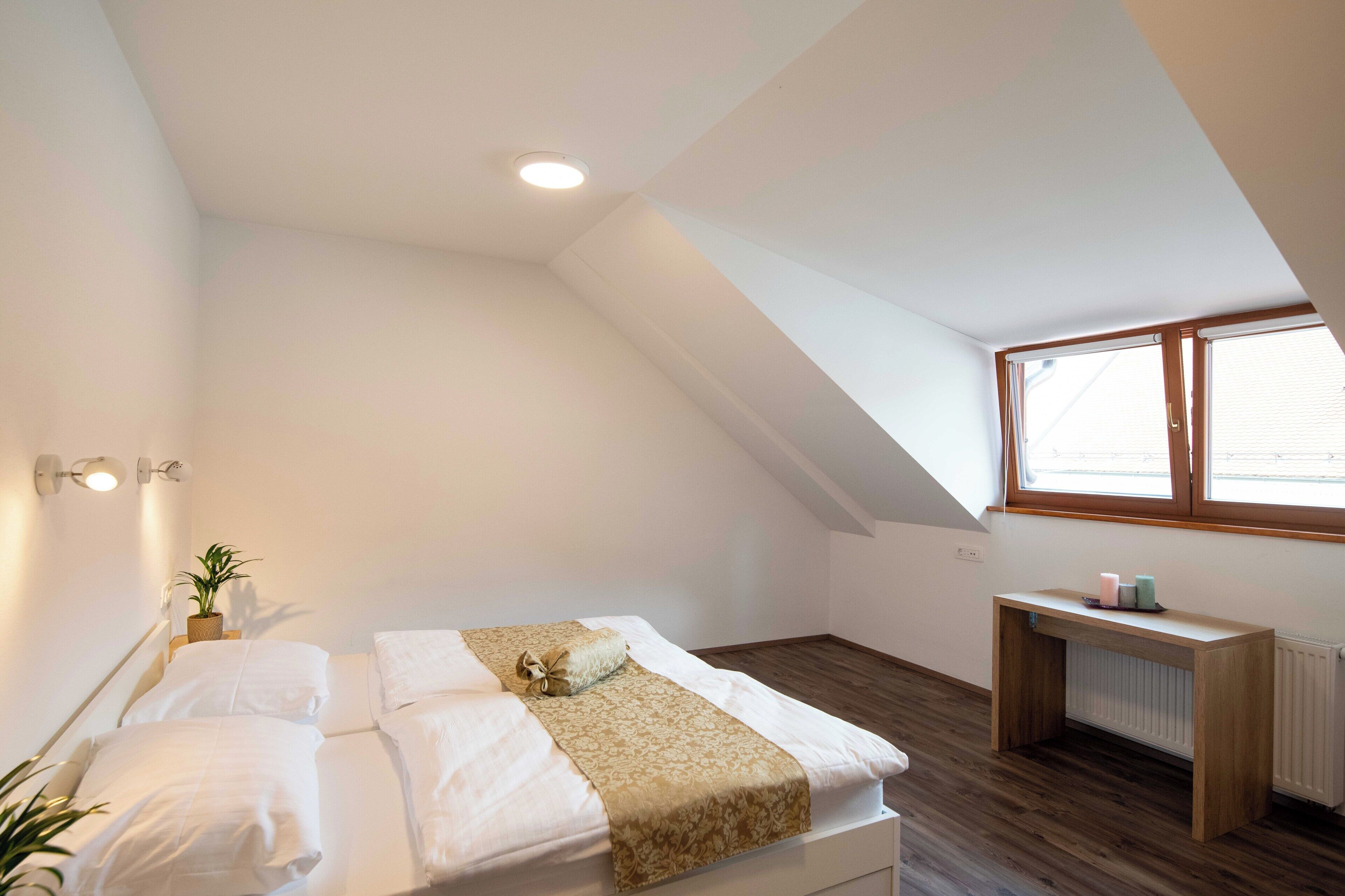 A bedroom with a bed, bedside table, and a window.
