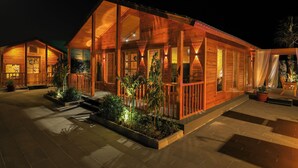 A wooden cabin with a covered porch, large windows, and potted plants. - elmurooj cottage (Jeddah)