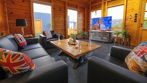 A cozy cabin interior with a wooden interior, a sofa set, a coffee table, and a television. - elmurooj cottage (Jeddah)