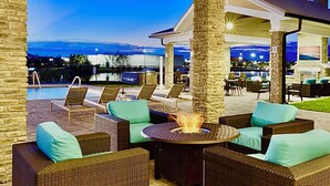 An outdoor patio area with wicker furniture, a round table with a fire feature, and a view of the water and mountains at dusk. - Cozy 2-bedroom apartment in nice Jacksonville with WiFi, fitness room - Sleep 6! (Jacksonville)