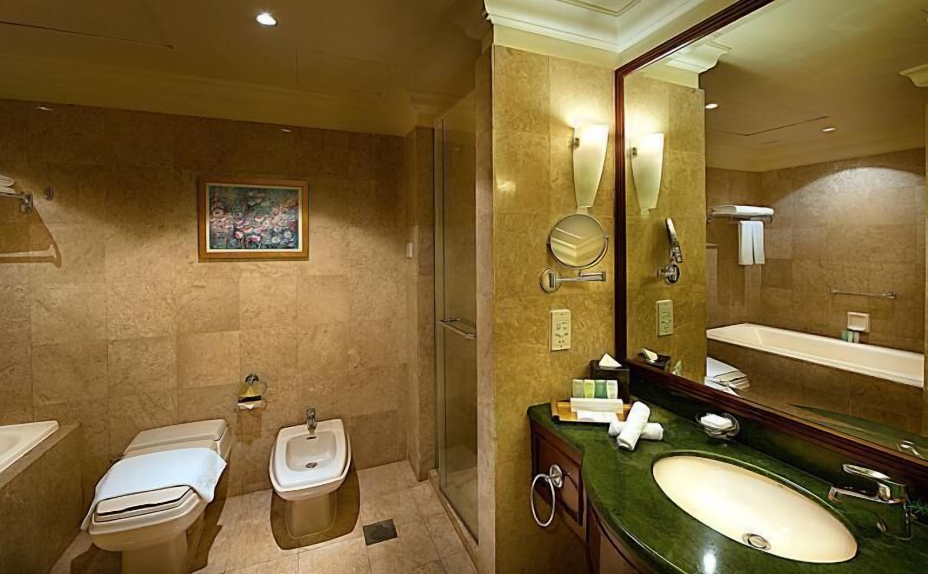 Et moderne badeværelse med et stort spejl, en bidet, en vask og en brusekabine.
