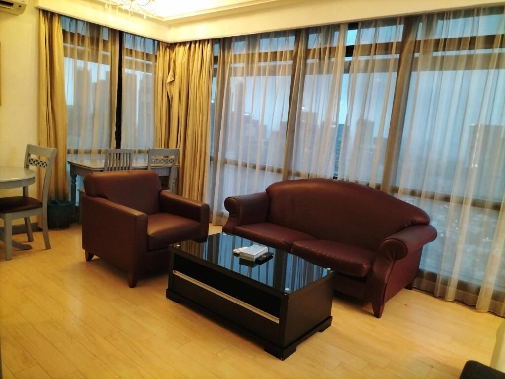Ein Wohnzimmer mit Glastisch, zwei Sesseln und einer Couch.