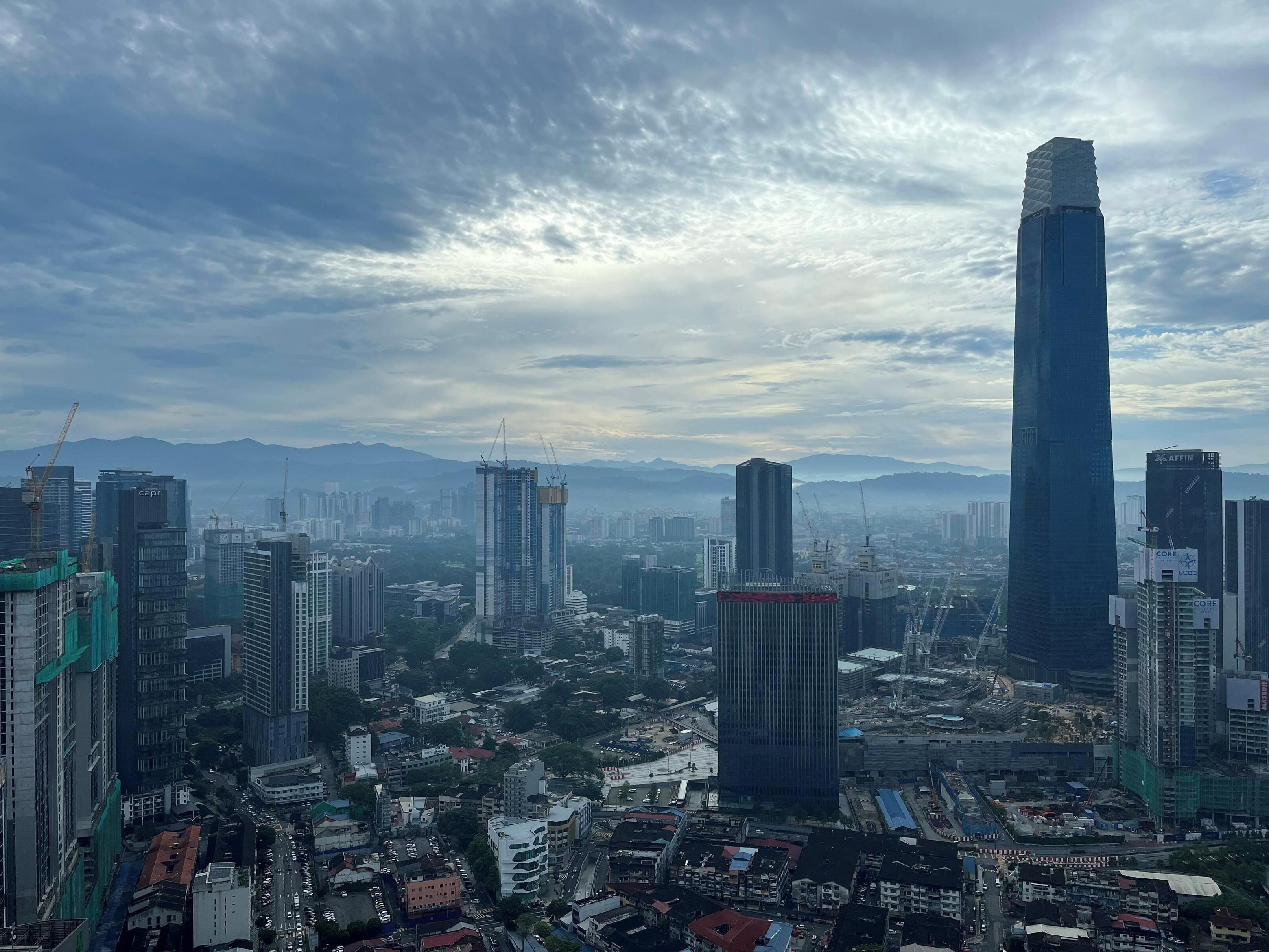 Un paysage urbain avec de nombreux immeubles de grande hauteur, dont un gratte-ciel remarquable qui se distingue par son design original au sommet.