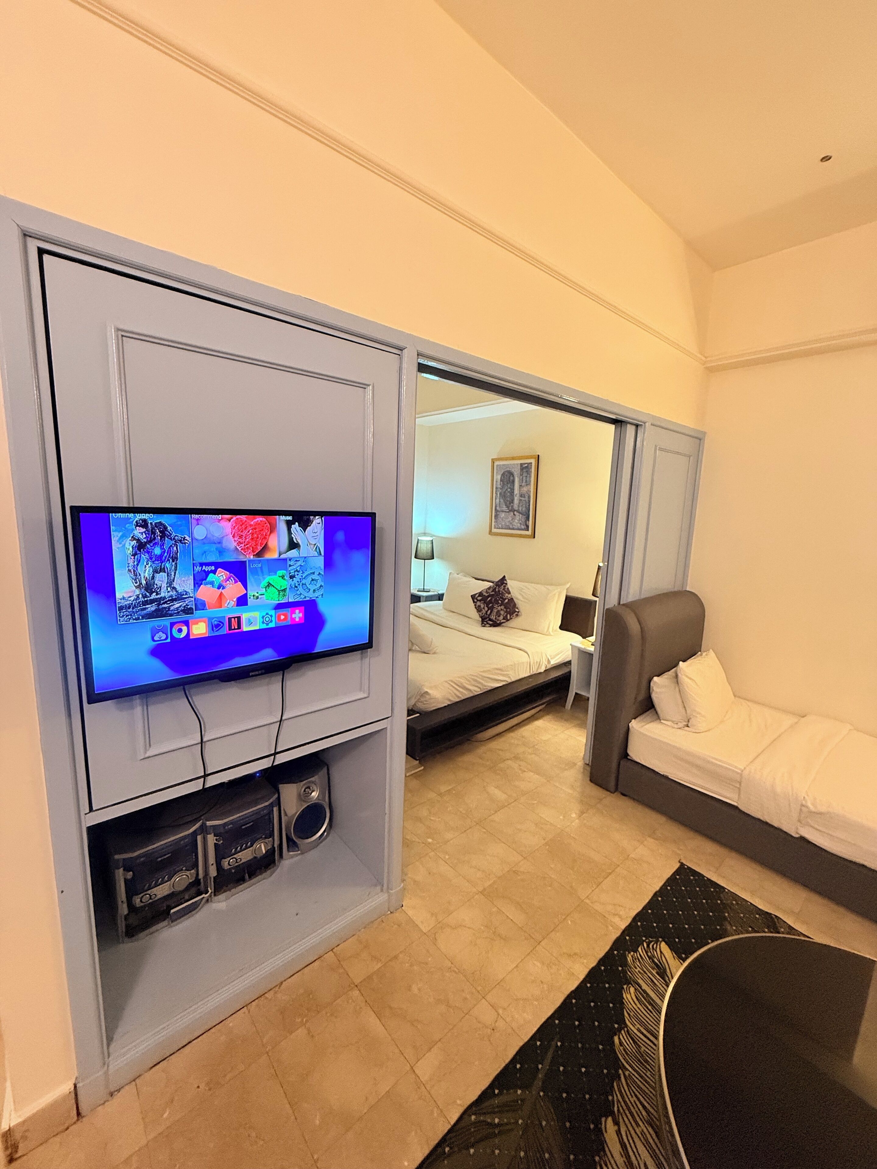 A hotel room with a television, a bed, a sofa, and a small table.