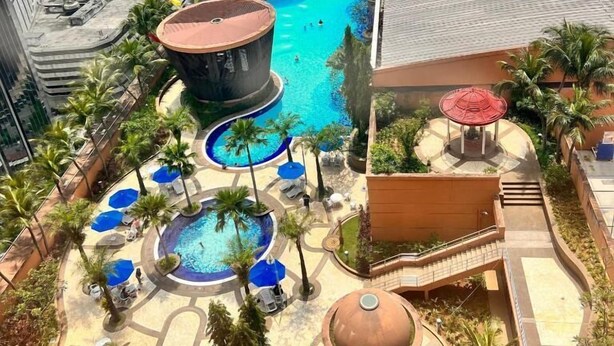 A rooftop pool area with multiple pools, palm trees, and lounge chairs. - KL Grand Service Suite at Times Square (Kuala Lumpur)