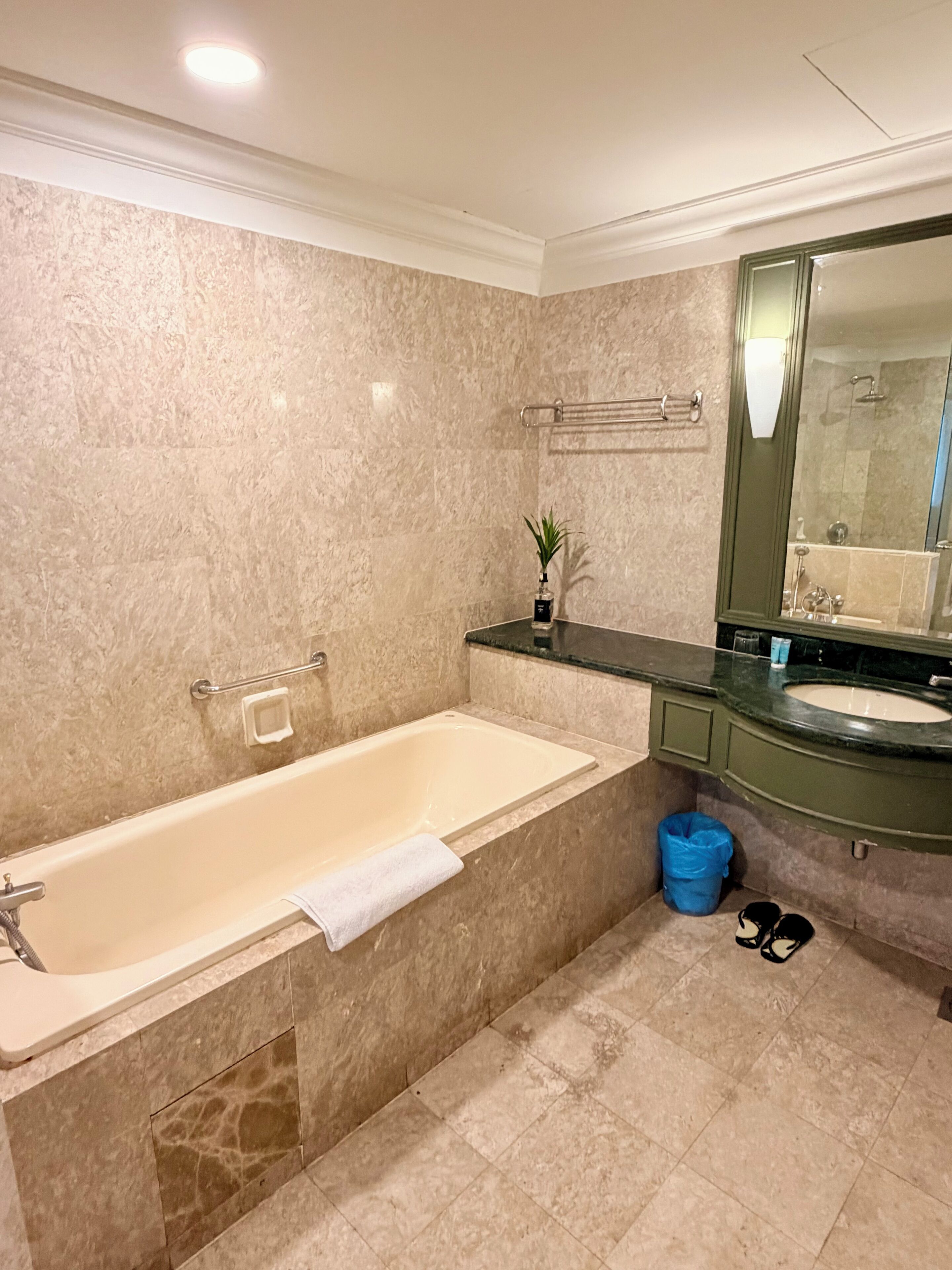 Un baño con bañera, lavamanos, espejo y toallero.