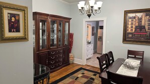 A dining room with a wooden table, chairs, a chandelier, and a patterned rug. - Spacious 3-BR Bungalow with Full Amenities Near University Area (Charlotte)