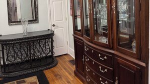 A room with a dark wooden cabinet with glass doors, a white door, and a black console table with a glass vase. - Spacious 3-BR Bungalow with Full Amenities Near University Area (Charlotte)