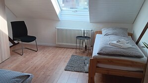 Huoneessa on kattovalaisin, sänky, tuoli, pieni pöytä ja patteri.