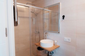 A modern bathroom with a glass shower enclosure, a white sink, and a wooden vanity. - Beachfront penthouse apartment with views of Albufera and incredible sunsets! (El Perelló)