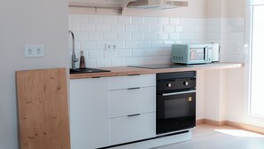 A modern kitchen with white cabinets, a wooden countertop, a built-in microwave, and a stainless steel range hood. - Penthouse apartment on the beach overlooking Albufera with incredible sunsets! (El Perelló)