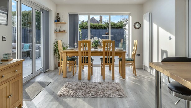 A modern dining area with a skylight, wooden furniture, and a view of the backyard.