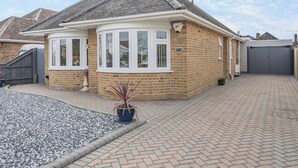 A two-story house with a brick exterior, a tiled roof, and a driveway leading to a gated entrance.