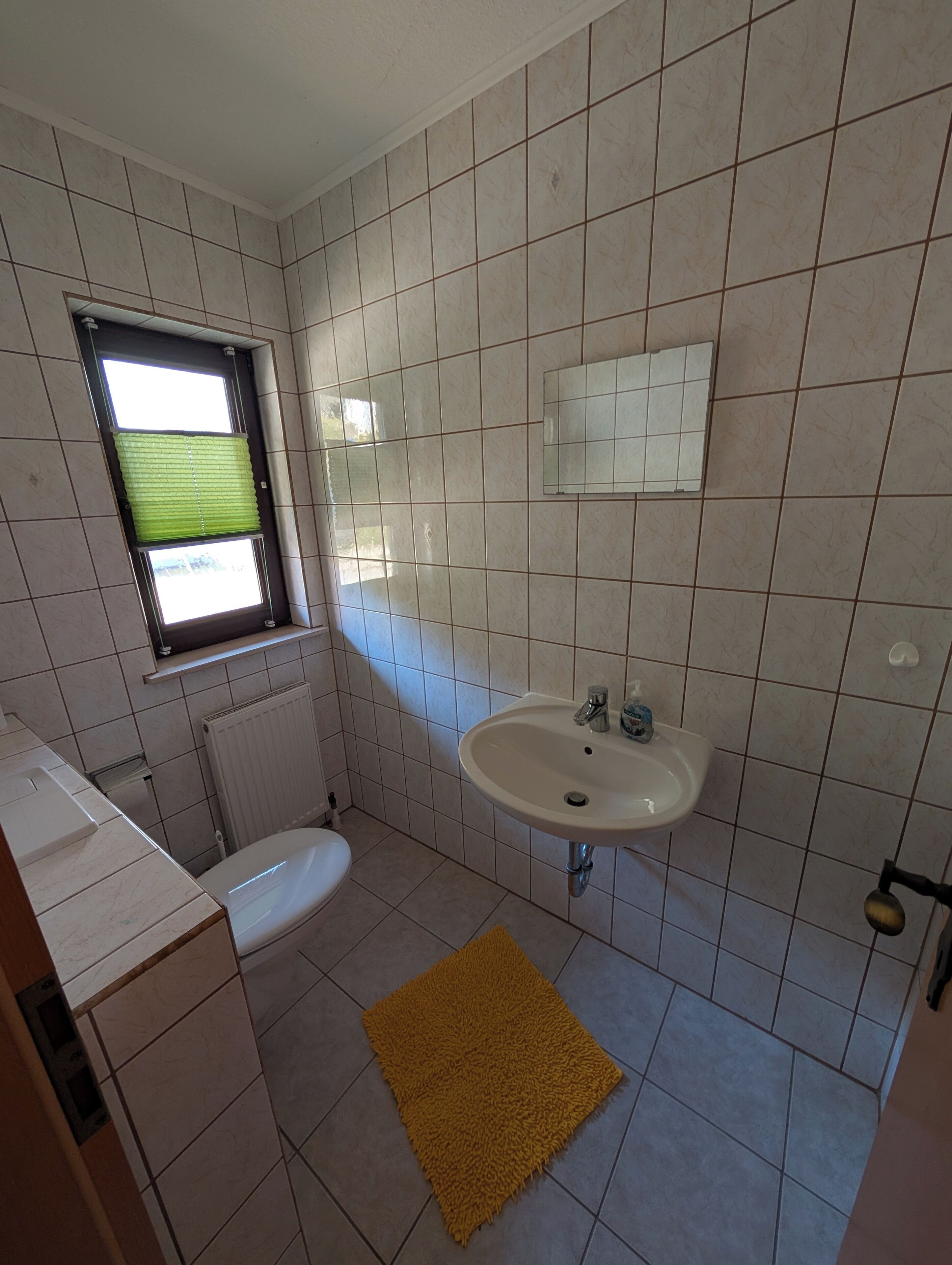 A bathroom with a toilet, sink, and window.