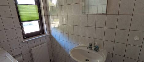A bathroom with a toilet, sink, and window.