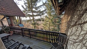 A wooden deck with a black railing, a table, and two chairs. - Family-friendly vacation home Bornholzweg in Quedlinburg - 157 sqm (Quedlinburg)