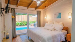 A bedroom with a large bed, wooden ceiling, and a view of a pool and outdoor furniture. - New Luxury Villa 8 min beach walk Pool+Grill Near West Bay (Roatan)