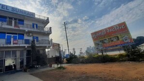 A hotel named 'Sunram' with a signboard, a large billboard advertising a restaurant, and a clear sky. - Hotel Sunrahi (Nagina)