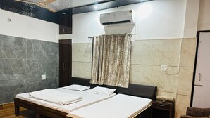 A double bed with a wooden frame, a small bedside table, and a chair. - Hotel Sunrahi (Nagina)