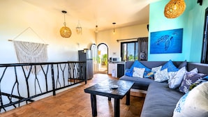 A living room with a sofa, coffee table, and a view to the outside. - One bedroom suite in Punta Sur (Isla Mujeres)