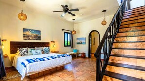 A bedroom with a bed, a ceiling fan, a window, and a staircase. - One bedroom suite in Punta Sur (Isla Mujeres)