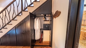 Un escalier avec une rampe en bois, une porte noire et un mur blanc orné d’une décoration représentant un poisson.