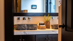 A bathroom with a marble sink, a mirror, and a wooden cabinet. - 1BR Studio w/balcony in Punta Sur (Isla Mujeres)
