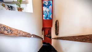 A staircase with a red accent wall, a wooden handrail, and a painting above the steps. - 2BR Suite in Punta Sur w/Pool (Isla Mujeres)