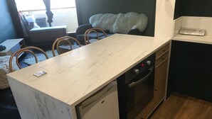 Una cocina compacta con encimera de mármol, lavavajillas, horno y fregadero.
