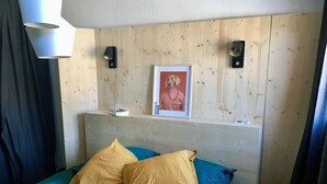 Un dormitorio con cabecera de madera, un cuadro enmarcado y dos almohadas.