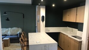 Una cocina compacta con encimera de mármol, armarios de madera y horno empotrado.