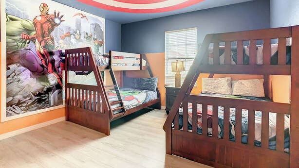 Une chambre d’enfant avec des lits superposés, une peinture murale au plafond et une fenêtre avec des stores.