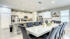 A modern kitchen with white cabinets, stainless steel appliances, and a central island with seating. - Oakwood Oasis (Davenport)