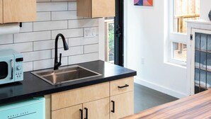 A modern kitchen with wooden cabinets, a black countertop, and a stainless steel sink. - Hilldale Studio - in the heart of Marin County (San Anselmo)