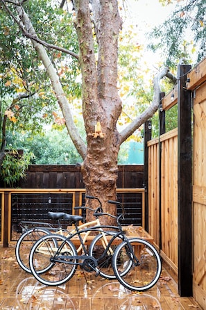 Bicycles are stored against a fence in the backyard.