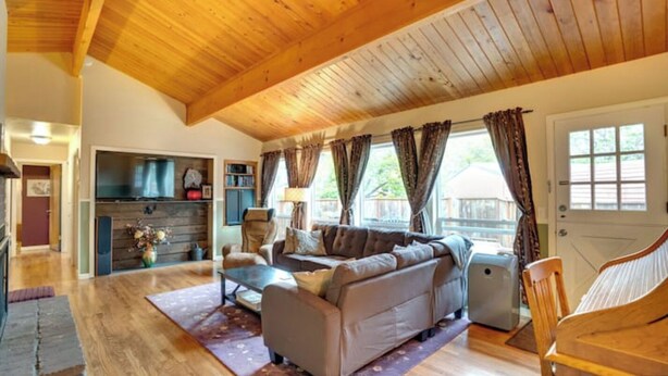 Un vaste espace de vie doté d’un plafond en bois, d’un ensemble de canapés, d’une table basse et d’une cheminée.