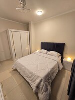 A bedroom with a bed, bedside lamps, a wardrobe, and a ceiling light.