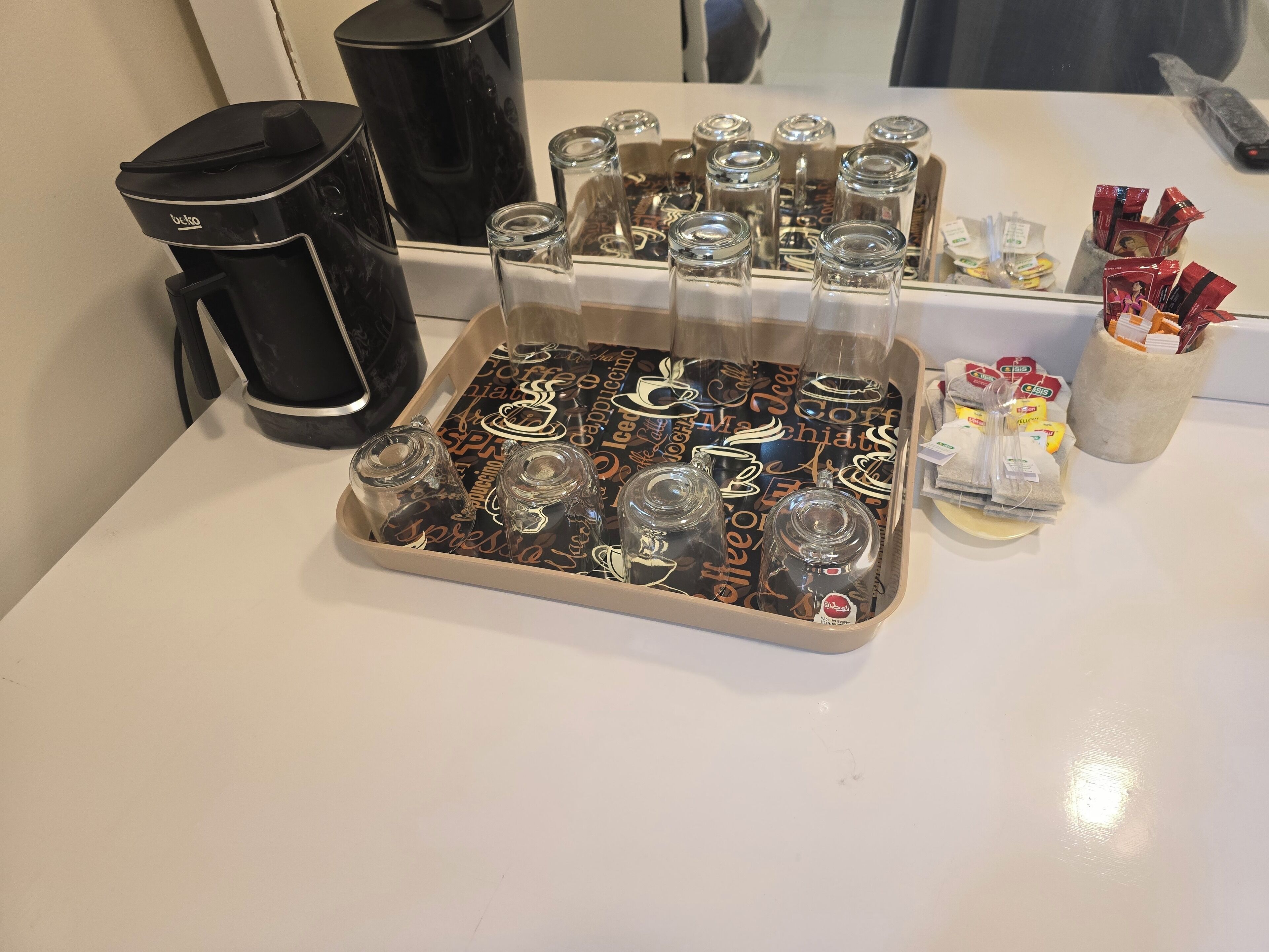 Una bandeja con tazas de café y una cafetera sobre una mesa.