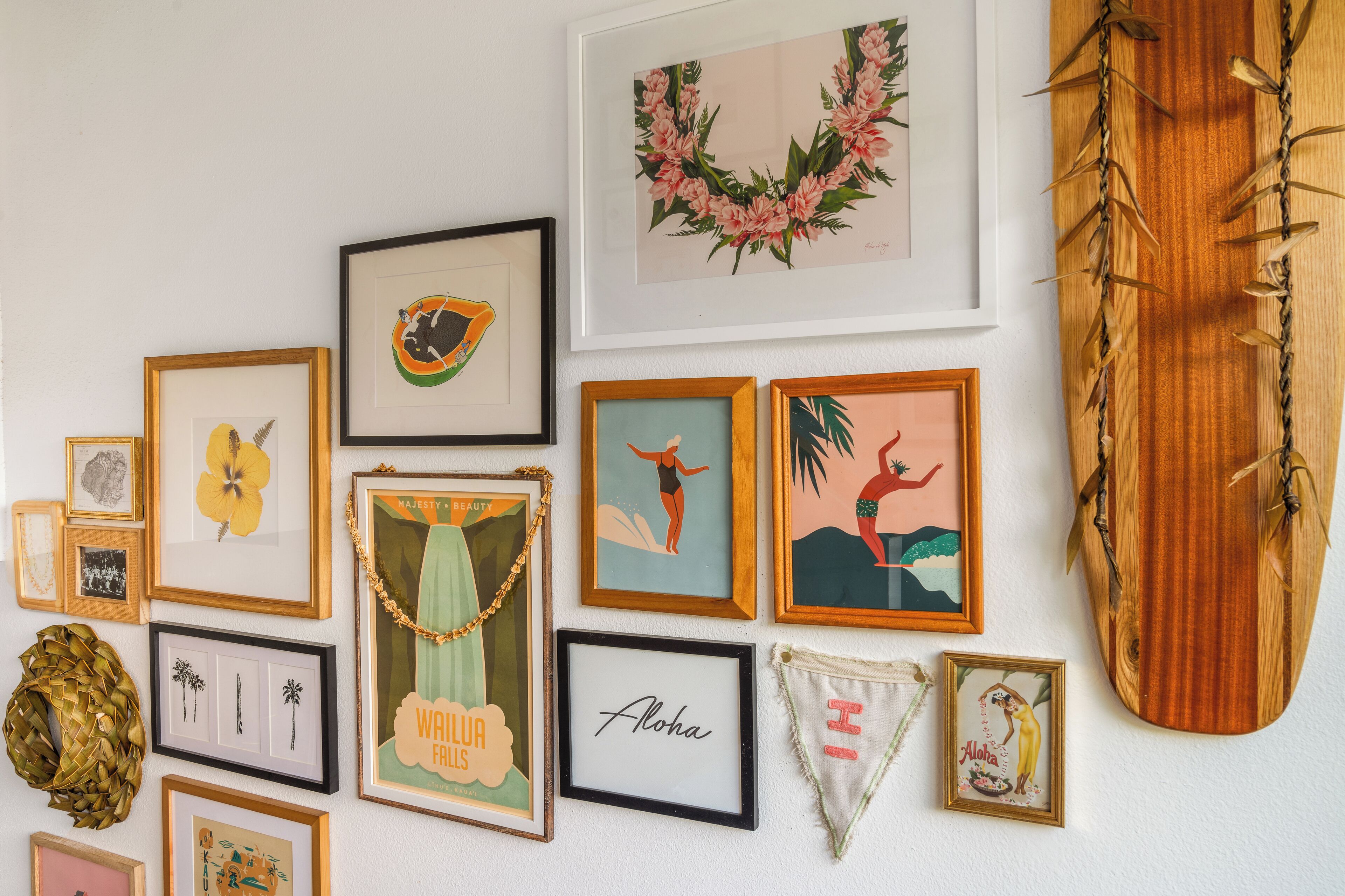 A wall with various framed artworks and a wooden board.