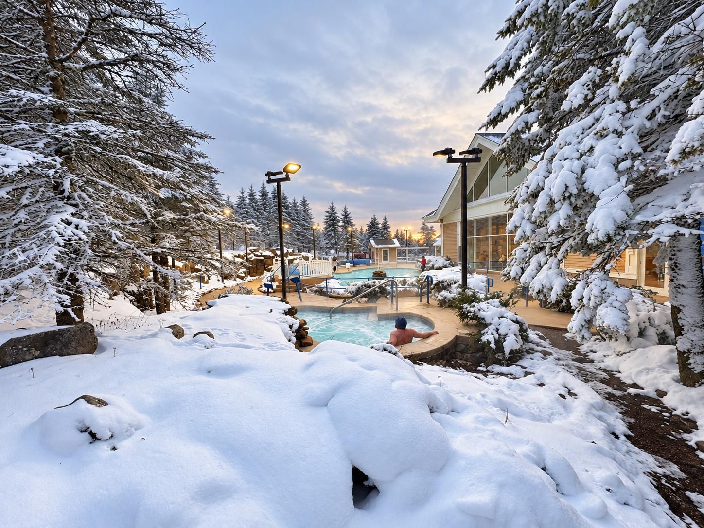 A snow-covered outdoor area with a pool, surrounded by trees and buildings.