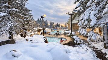 A snow-covered outdoor area with a pool, surrounded by trees and buildings.