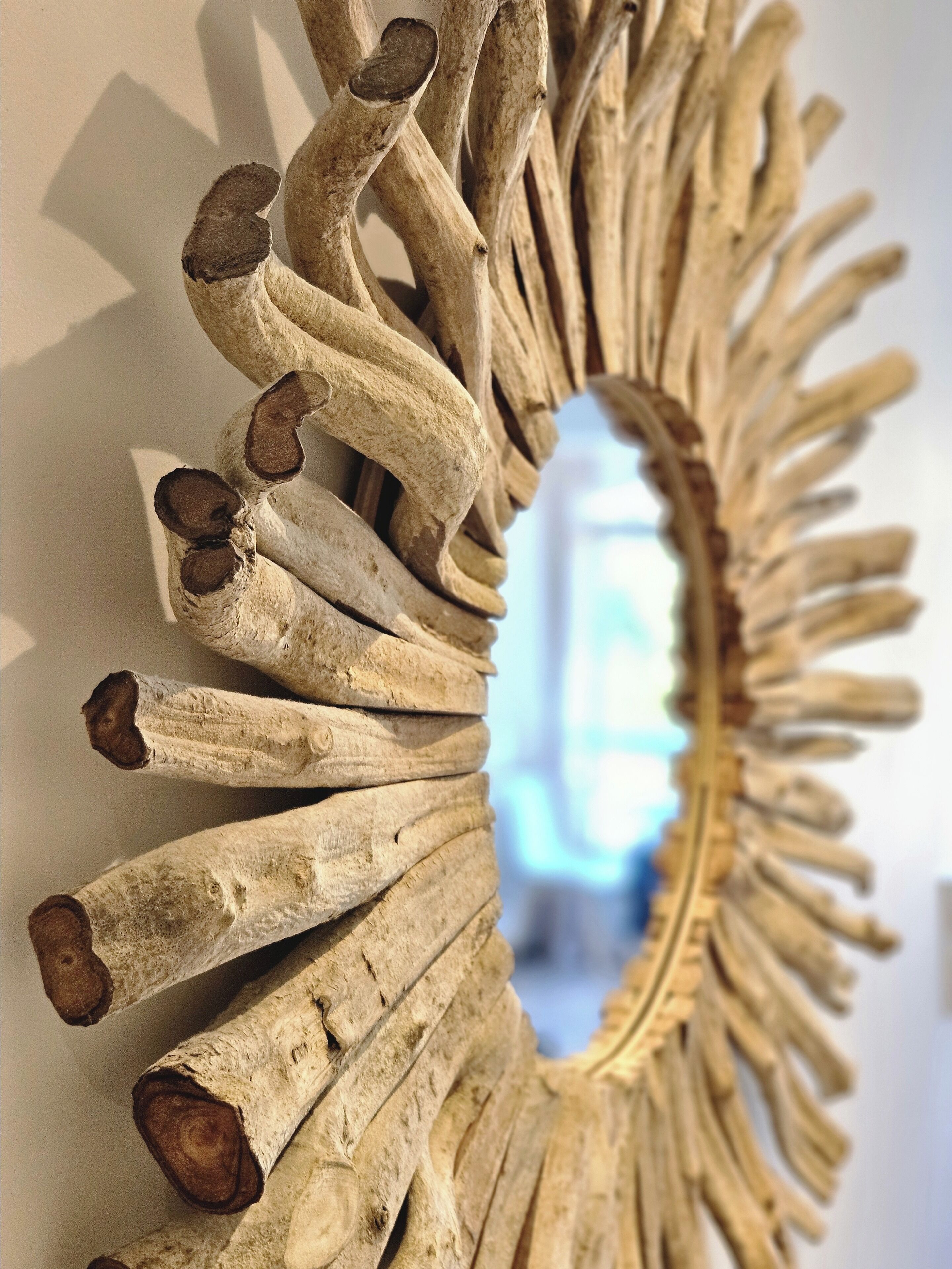 A wall-mounted mirror with a sunburst design made from wood.