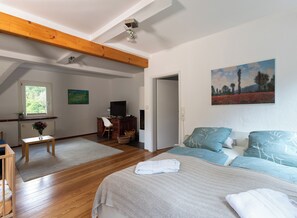 Une chambre à coucher avec un lit, un bureau, une chaise et un tableau accroché au mur.