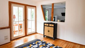 Una stanza con pavimento in legno, un armadio nero e in legno e un grande specchio appeso al muro.