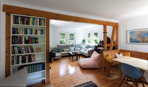 Un salon avec un plancher en bois, un canapé, une table basse, une bibliothèque et un tableau accroché au mur.