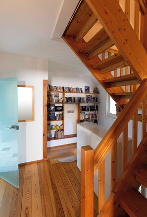 A wooden staircase leading to a library with bookshelves and a ladder.