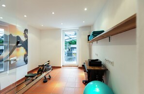 Un gimnasio con equipamiento de ejercicio, una máquina de remo y una pelota de ejercicio verde.
